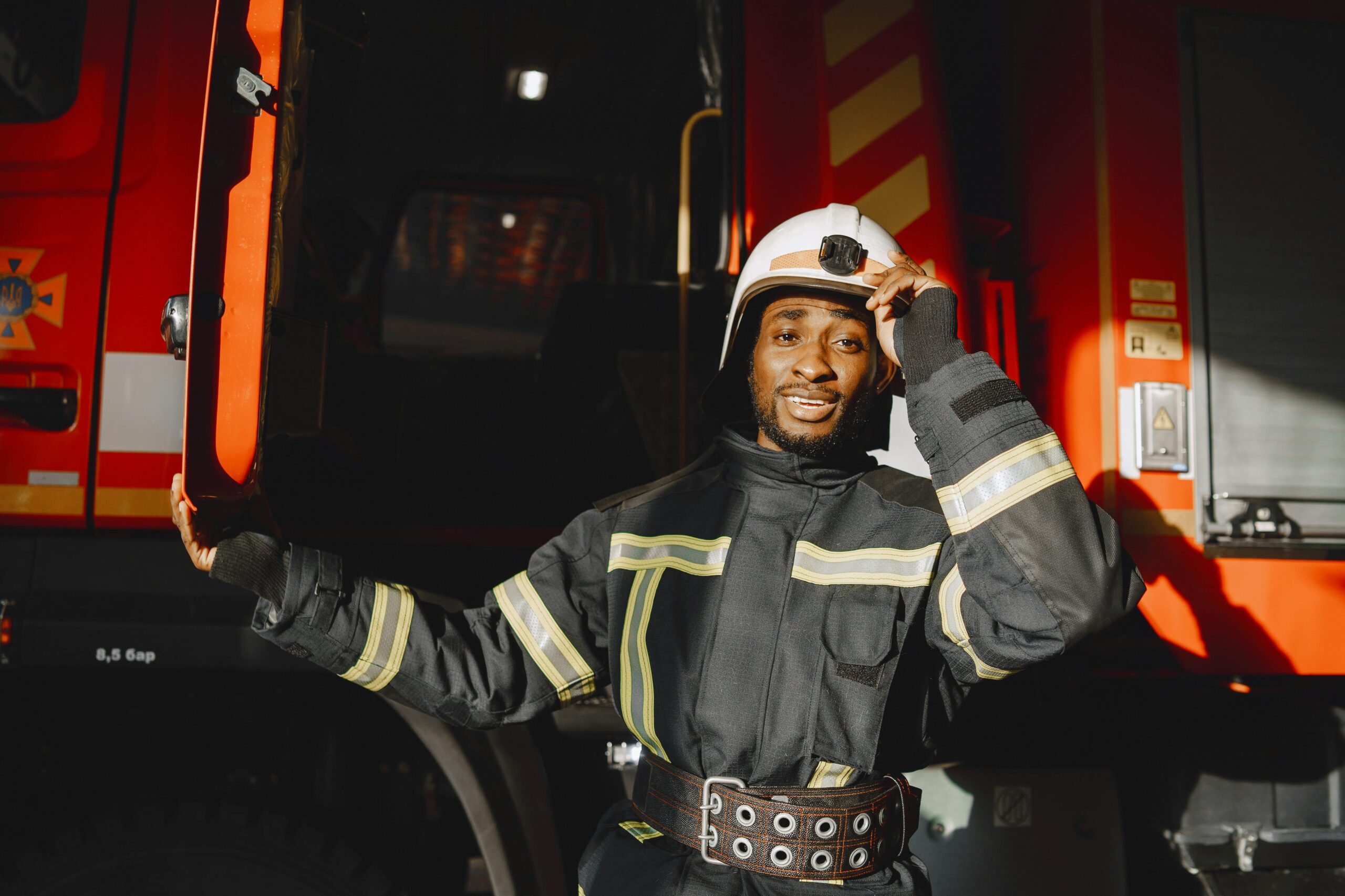 Close-up of a firefighter in uniform posing confidently by a fire truck, showcasing bravery and professionalism.