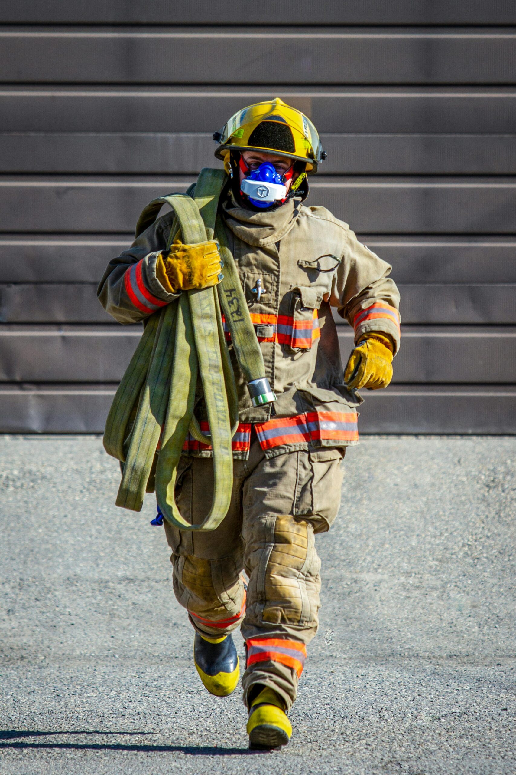 Brave firefighter in full gear, running with hose for emergency response.